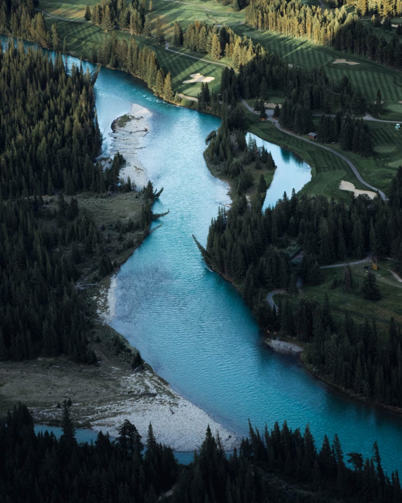 a photo of a beautiful blue river running in the landscape below tunnel mountain