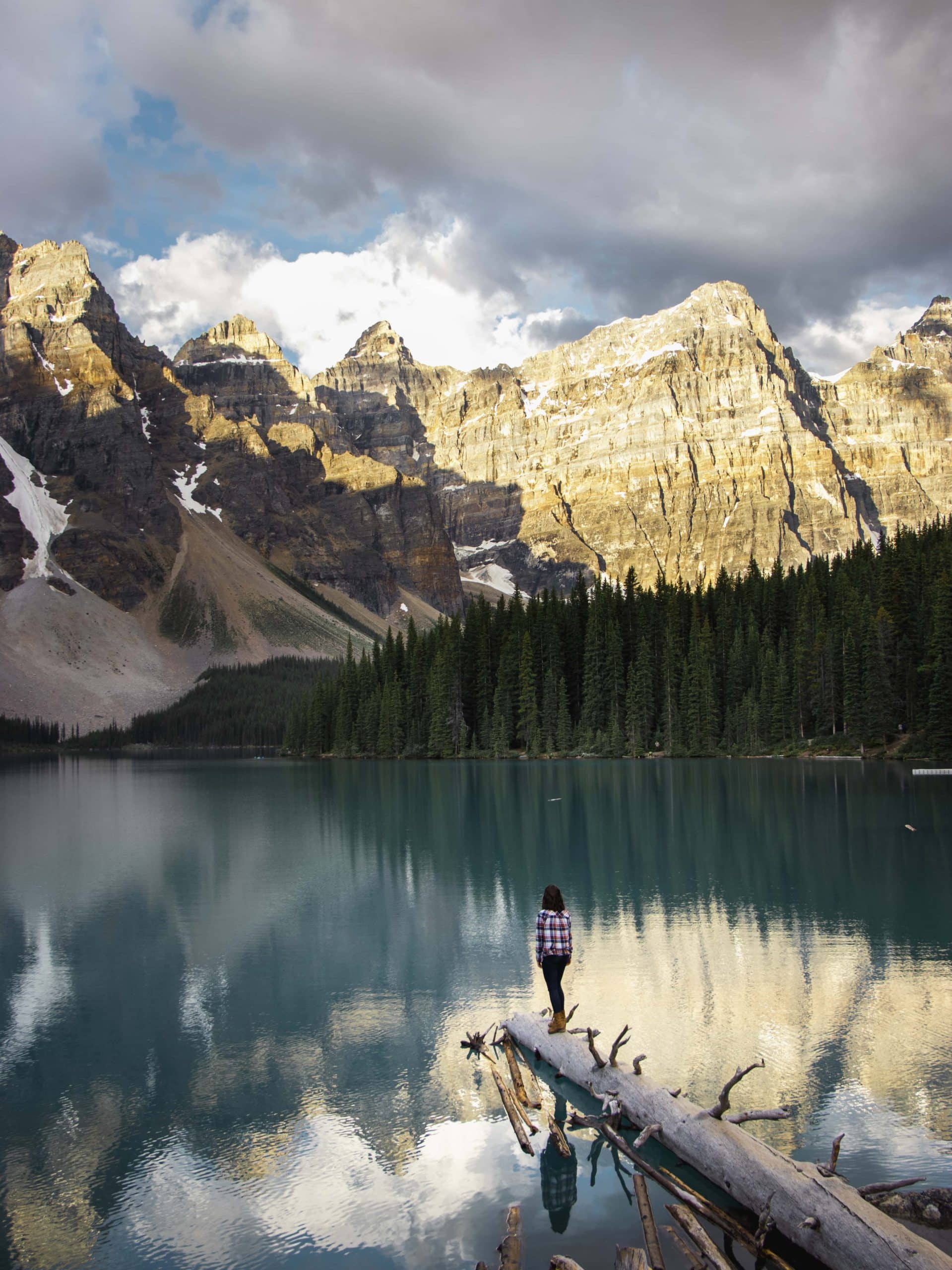 a photo of a girl walking out on a log at Moraine Lake, Banff National Park - best stops on the icefields parkway canada, drive the icefields parkway, icefields parkway stops