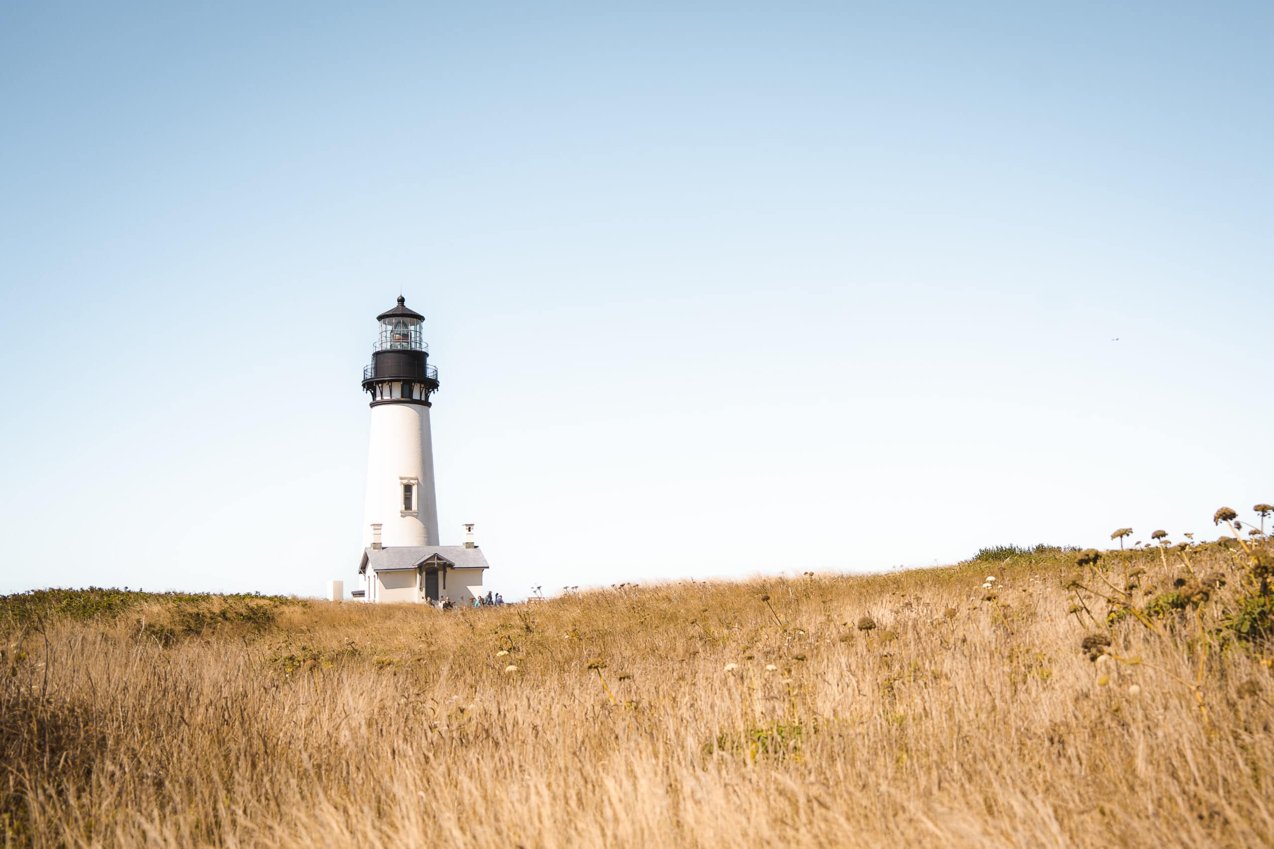 a view of Yaquina Head Lighthouse on the Oregon Coast, this is one of the prettiest lighthouses and you need to add it to your 10 day oregon road trip itinerary