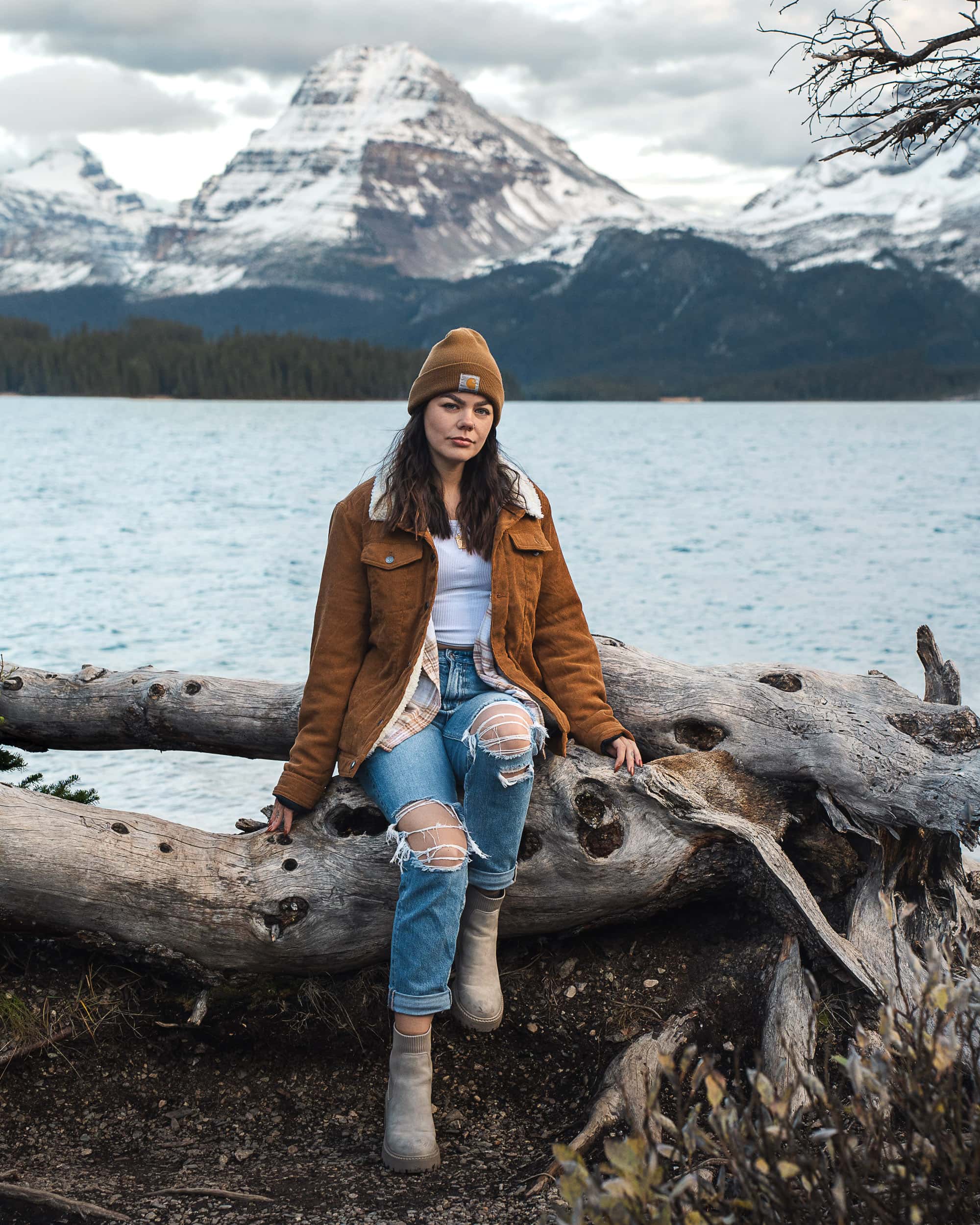 sitting on a log by bow lake with stunning mountains in the back